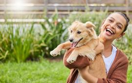 Image of lady holding a newly adopted golden retriever dog. Both lady and dog appear joyful.