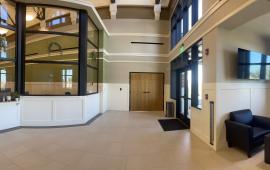 A picture taken from ground level that faces the LPD Lobby showing black chairs with multiple doors and glass windows.