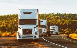 3 big rigs lined up on the side of a highway