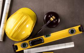 Yellow Construction Hat, Leveler, Rolled-up Plans and Legal Wood Gable on Wood Table