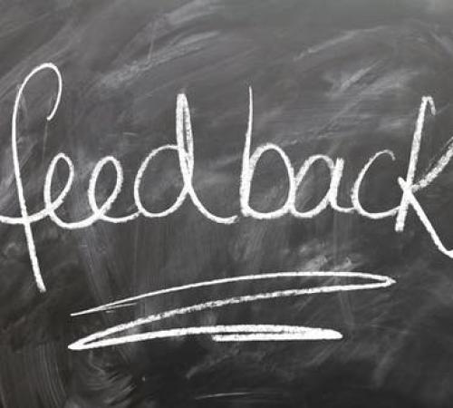 The word "Feedback" written on a chalkboard with white chalk