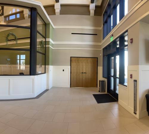 A picture taken from ground level that faces the LPD Lobby showing black chairs with multiple doors and glass windows.