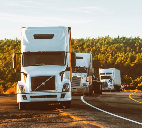 3 big rigs lined up on the side of a highway