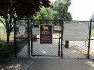 Cyclone entrance gate to large dog area with posted rules at Lathrop Dog Park at River Park South