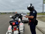 A Lathrop police officer examines a citation next to a police motorcycle with its lights activated