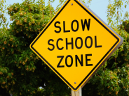 A bright yellow caution with text "SLOW SCHOOL ZONE"