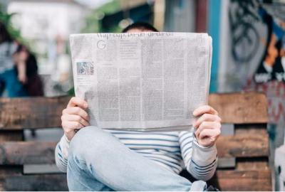 Person reading a newspaper on a public bench