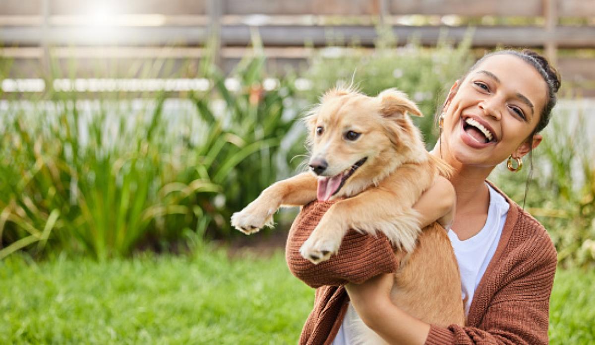 Image of lady holding a newly adopted golden retriever dog. Both lady and dog appear joyful.