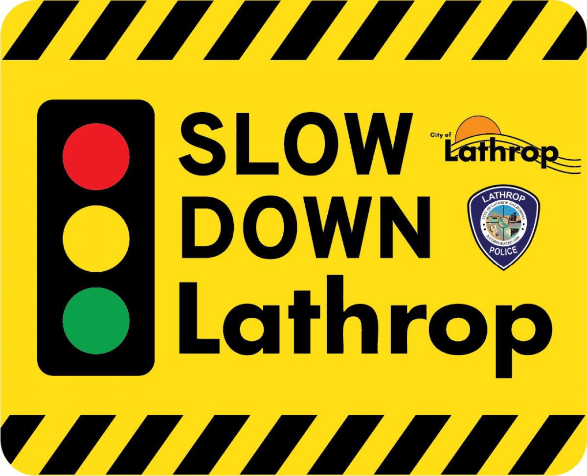 A bright yellow traffic sign with an illustrated traffic signal light and text "Slow Down Lathrop"