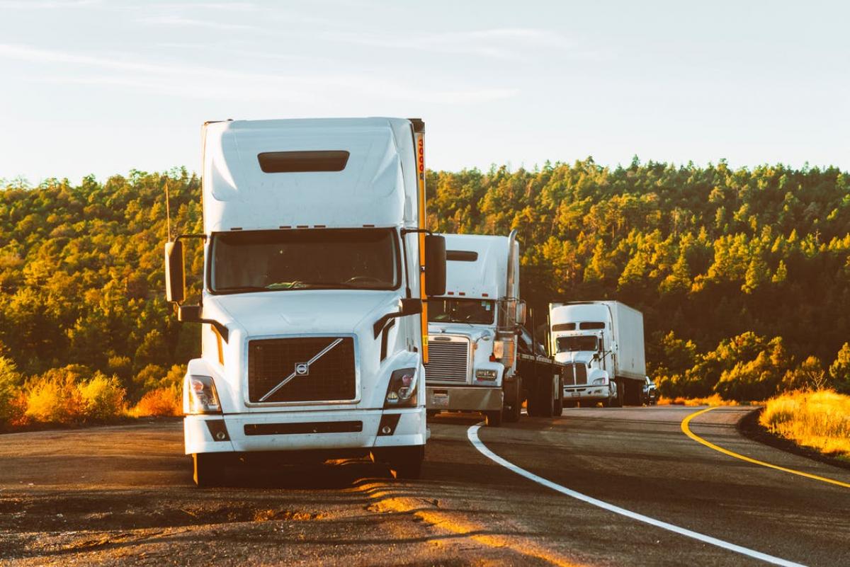 3 big rigs lined up on the side of a highway