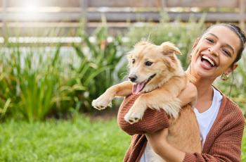 Image of lady holding a newly adopted golden retriever dog. Both lady and dog appear joyful.